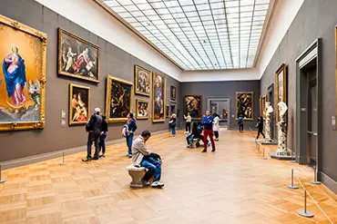 An art museum gallery with a patron looking at the paintings.