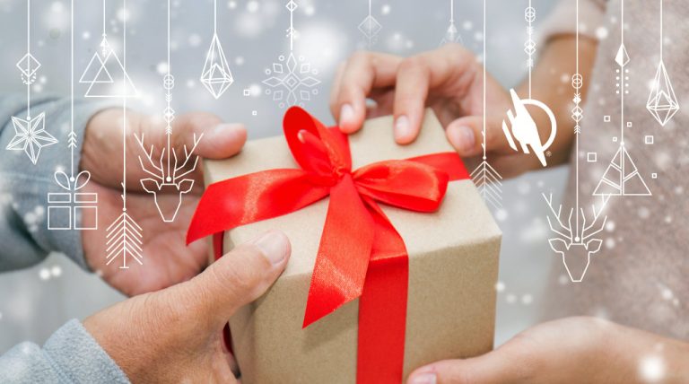 Older persons hands on a wrapped Christmas package with red ribbon giving gift to younger person with their hands receiving the package. White outlines of various hanging ornament graphics on layer above gift giving image.