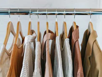 A series of hangers hanging from a metal bar. On each of the hangers are a series of shirts and jackets in a variety of brown shades.